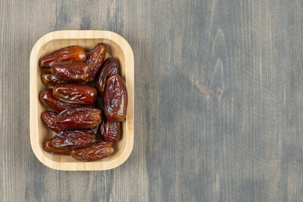 juicy dates in a wooden plate on a wooden table